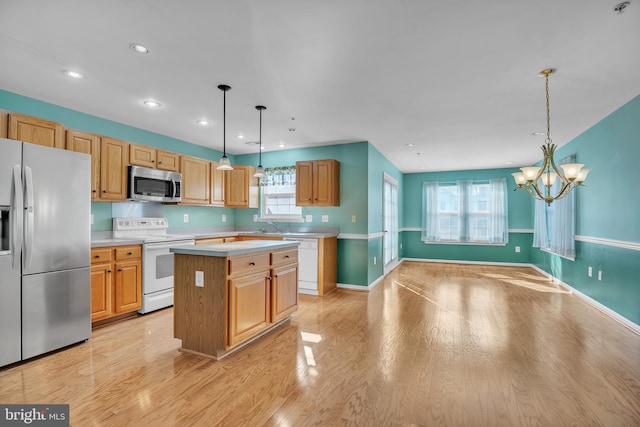 kitchen with appliances with stainless steel finishes, light wood-type flooring, a kitchen island, an inviting chandelier, and pendant lighting