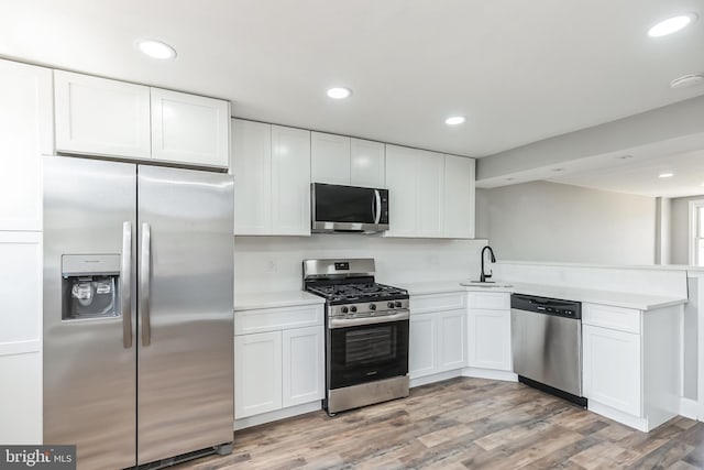 kitchen with white cabinets, sink, appliances with stainless steel finishes, and light hardwood / wood-style flooring