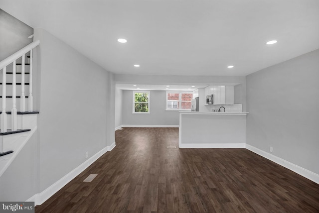 unfurnished living room featuring dark wood-type flooring and sink