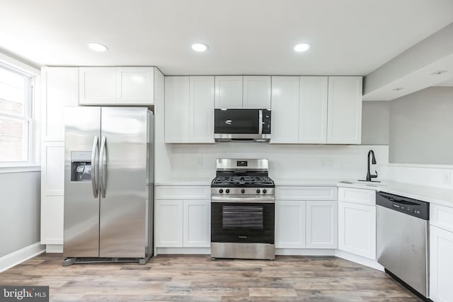 kitchen featuring stainless steel appliances, white cabinetry, and sink