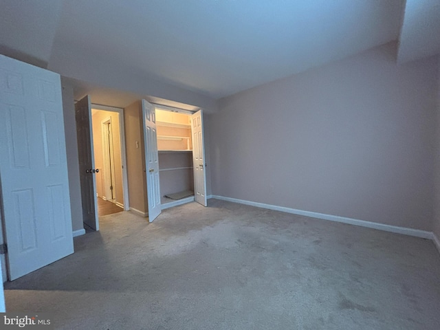 unfurnished bedroom with light colored carpet and a closet