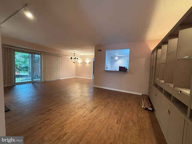 unfurnished living room with hardwood / wood-style flooring and a notable chandelier