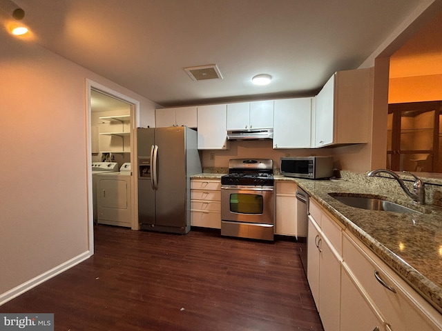 kitchen featuring washer and clothes dryer, white cabinets, stainless steel appliances, sink, and stone countertops