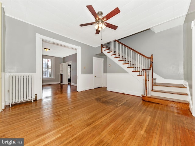 unfurnished living room with ceiling fan, wood-type flooring, crown molding, and radiator