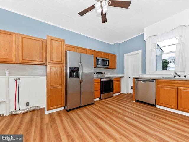 kitchen with backsplash, sink, ceiling fan, light wood-type flooring, and appliances with stainless steel finishes