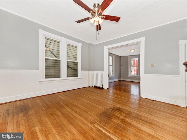 unfurnished room featuring hardwood / wood-style floors, radiator, ornamental molding, and ceiling fan