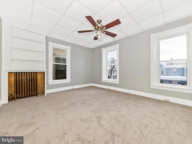 unfurnished living room featuring light carpet, radiator heating unit, a paneled ceiling, and ceiling fan