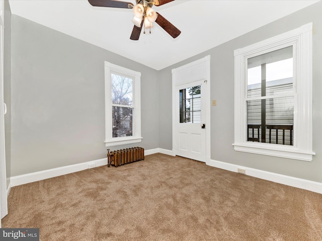 carpeted empty room featuring ceiling fan and radiator heating unit