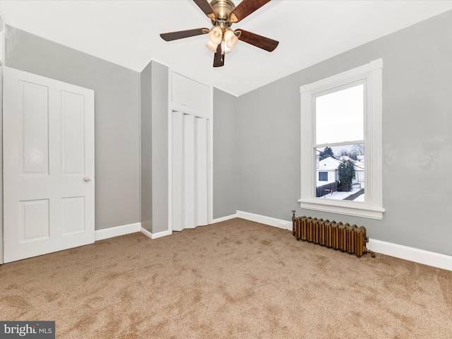 unfurnished bedroom with radiator, ceiling fan, and light carpet