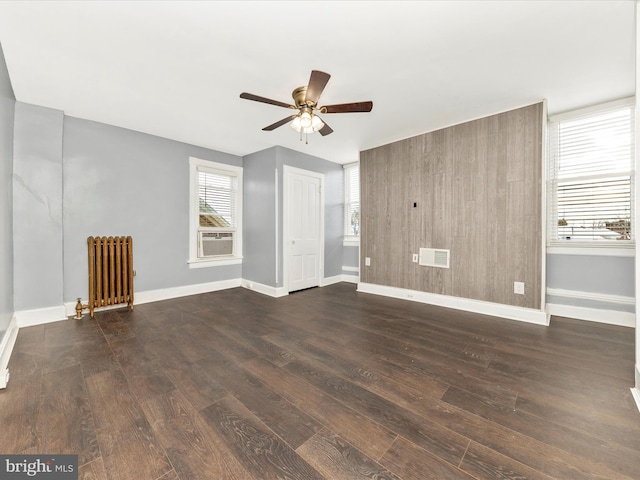 interior space with ceiling fan, cooling unit, radiator heating unit, and dark wood-type flooring