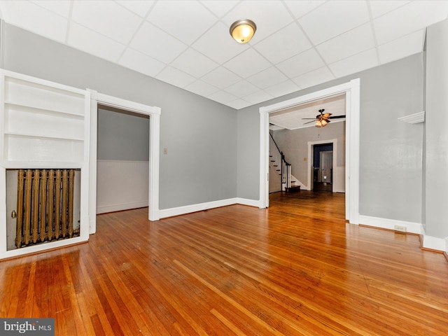 unfurnished living room with a paneled ceiling, ceiling fan, and hardwood / wood-style flooring