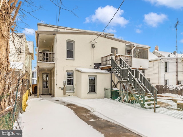 snow covered back of property with a sunroom