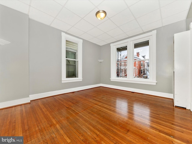 spare room with a drop ceiling and hardwood / wood-style flooring