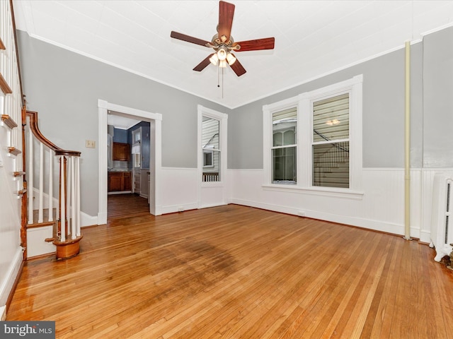 unfurnished living room featuring radiator heating unit, light hardwood / wood-style floors, ceiling fan, and crown molding