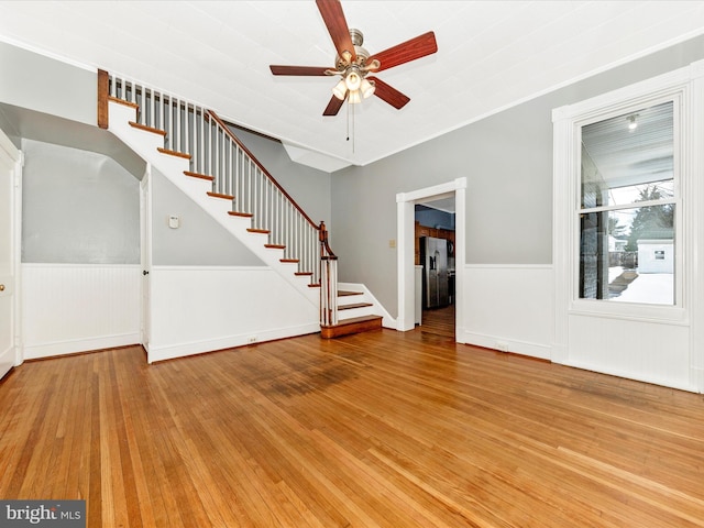 unfurnished living room featuring ceiling fan, crown molding, and wood-type flooring