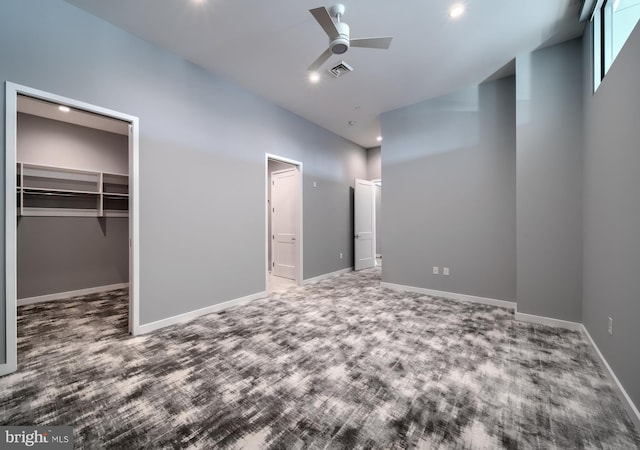 unfurnished bedroom featuring ceiling fan, carpet floors, a closet, and a spacious closet