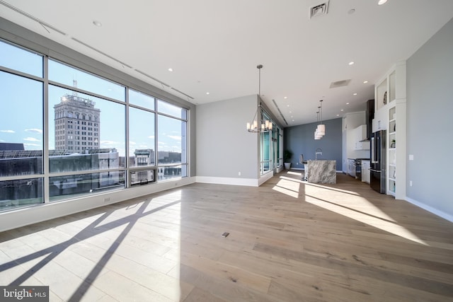 unfurnished living room featuring light hardwood / wood-style flooring and a notable chandelier