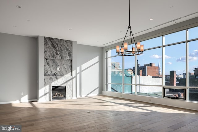 unfurnished living room with hardwood / wood-style flooring, a chandelier, and a fireplace