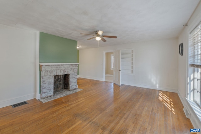 unfurnished living room featuring a textured ceiling, ceiling fan, a fireplace, and light hardwood / wood-style flooring