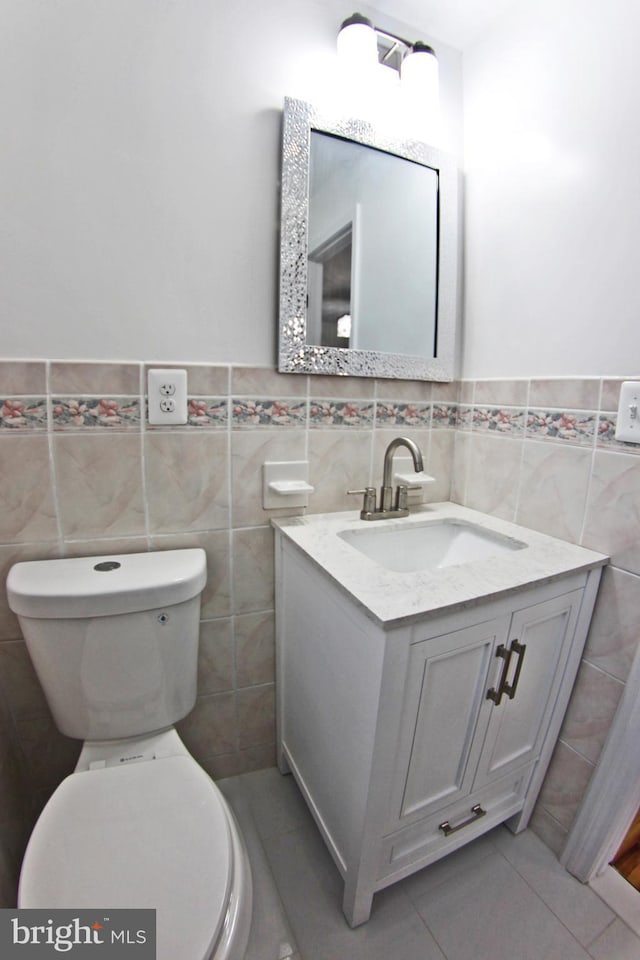 bathroom with tile patterned flooring, vanity, tile walls, and toilet