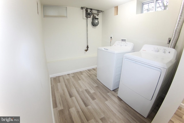 washroom with washing machine and clothes dryer and light hardwood / wood-style floors