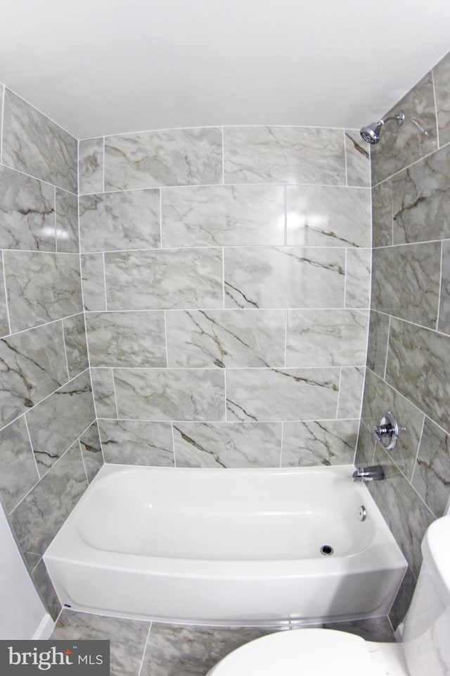 bathroom featuring toilet and tiled shower / bath