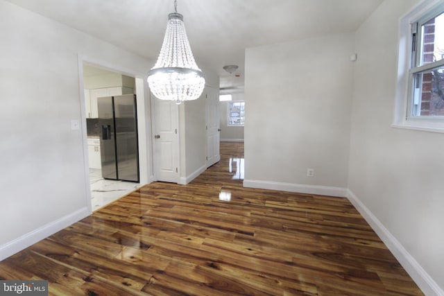 unfurnished dining area featuring wood-type flooring and a notable chandelier