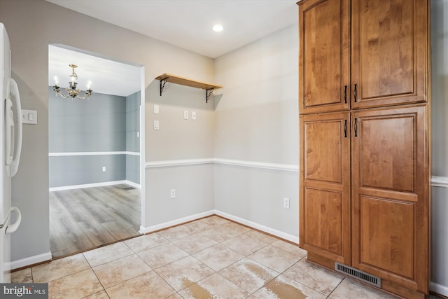 unfurnished dining area featuring light tile patterned floors and an inviting chandelier