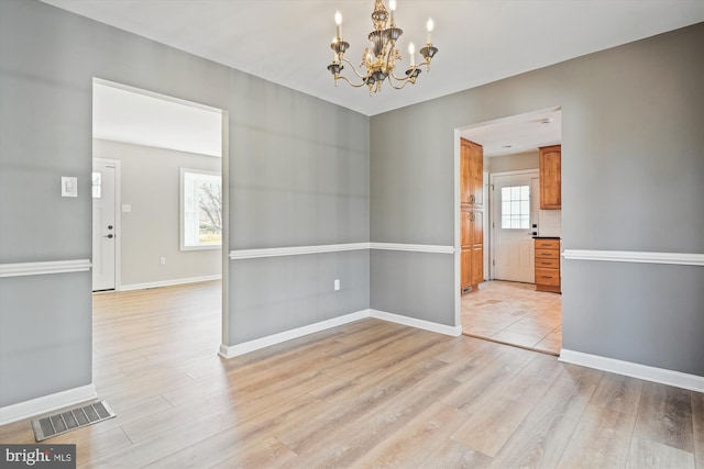 unfurnished room with a chandelier and light hardwood / wood-style flooring