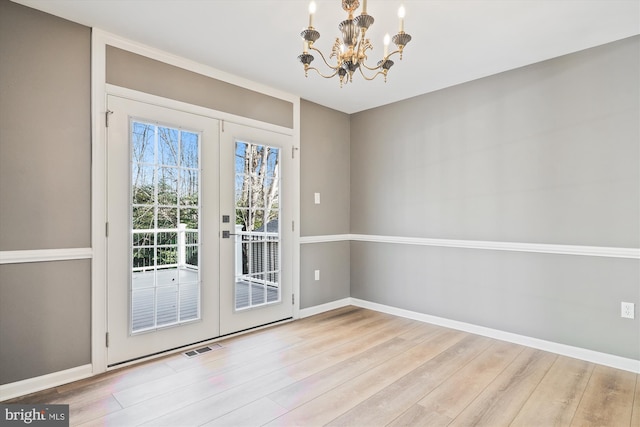 doorway to outside featuring french doors, light hardwood / wood-style flooring, and an inviting chandelier