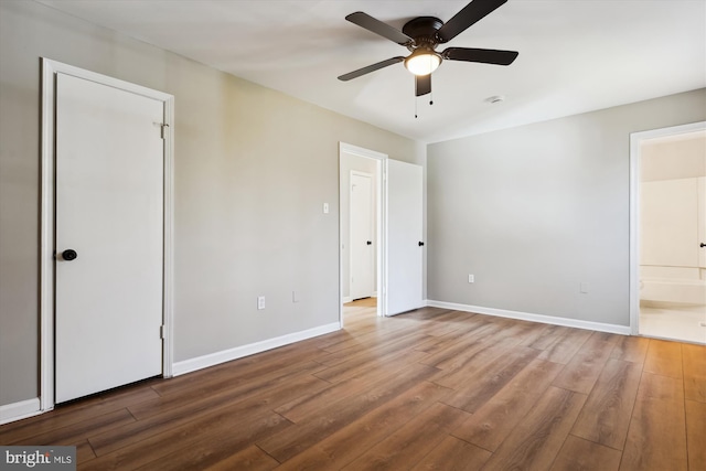 unfurnished bedroom with hardwood / wood-style floors, ceiling fan, and ensuite bath