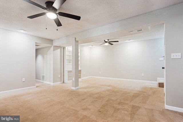 basement with ceiling fan and light carpet