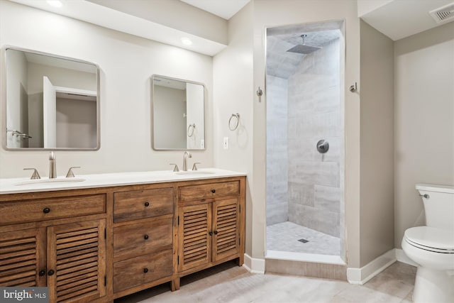 bathroom with tiled shower, tile patterned flooring, vanity, and toilet