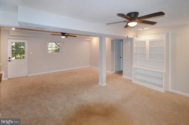 basement featuring ceiling fan and light colored carpet