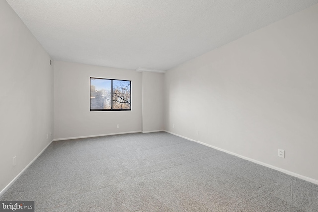 carpeted empty room featuring a textured ceiling