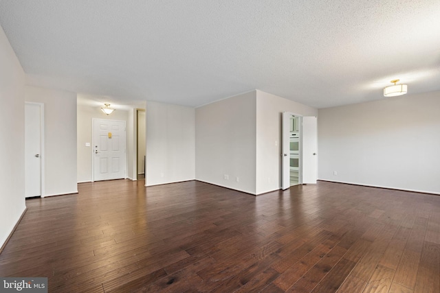 spare room with a textured ceiling and dark hardwood / wood-style flooring