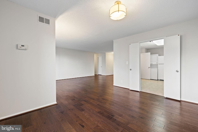 spare room with a textured ceiling and dark hardwood / wood-style flooring