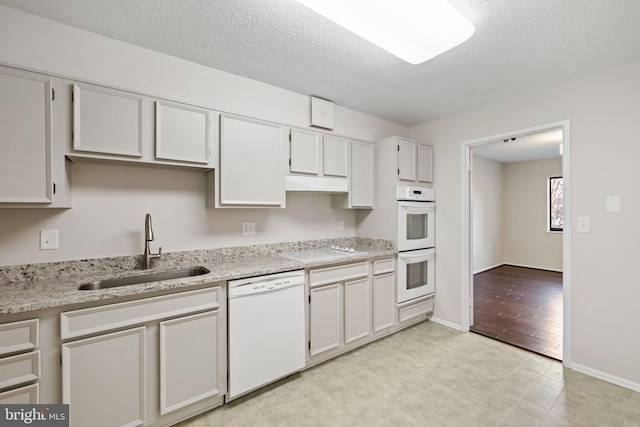 kitchen featuring sink, white cabinetry, a textured ceiling, white appliances, and light stone countertops