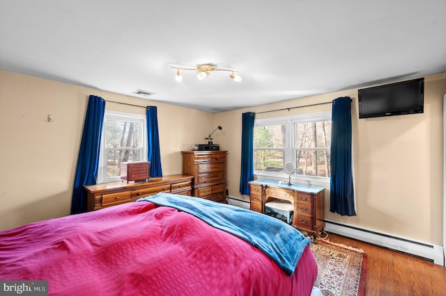 bedroom with wood-type flooring and a baseboard radiator