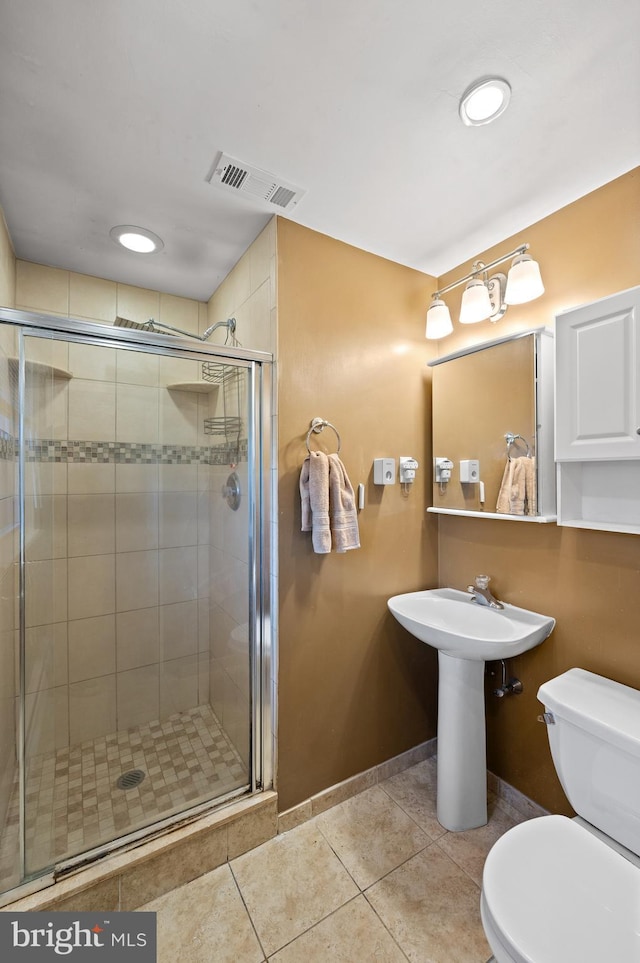 bathroom with tile patterned floors, a shower with door, and toilet