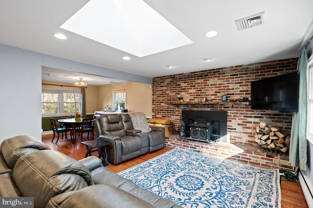 living room with hardwood / wood-style flooring, a wood stove, and brick wall