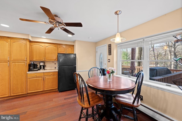 dining area featuring wood-type flooring, a baseboard radiator, and ceiling fan