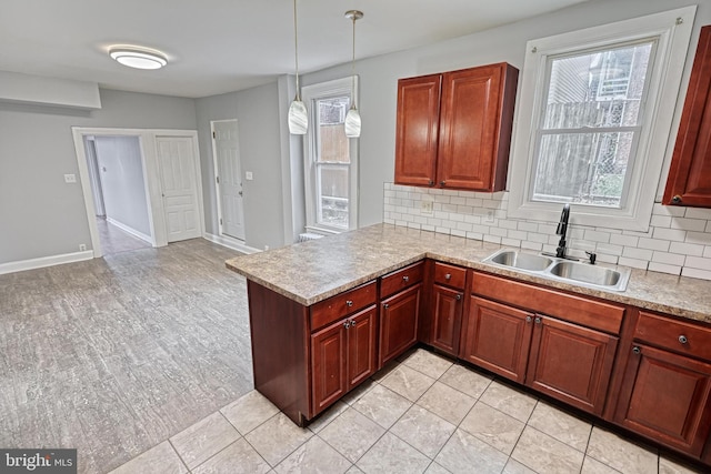 kitchen with kitchen peninsula, backsplash, decorative light fixtures, and sink