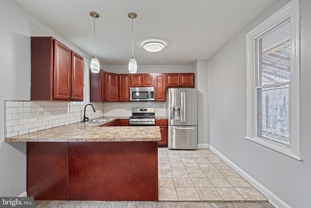 kitchen featuring sink, backsplash, kitchen peninsula, decorative light fixtures, and appliances with stainless steel finishes