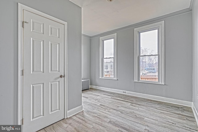 unfurnished bedroom featuring radiator, crown molding, and light hardwood / wood-style floors