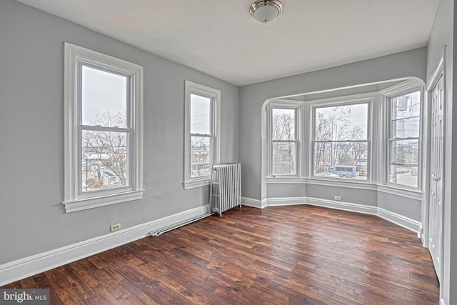 empty room with dark hardwood / wood-style floors and radiator