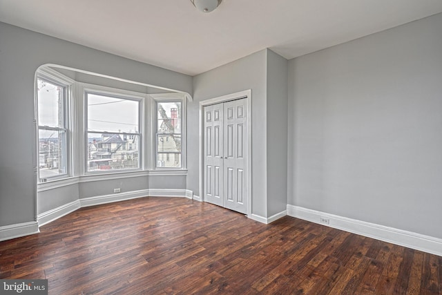 unfurnished bedroom with a closet and dark wood-type flooring