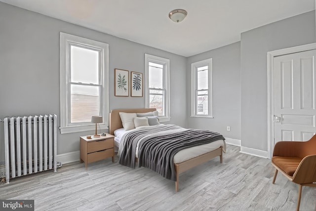 bedroom featuring radiator heating unit and light wood-type flooring