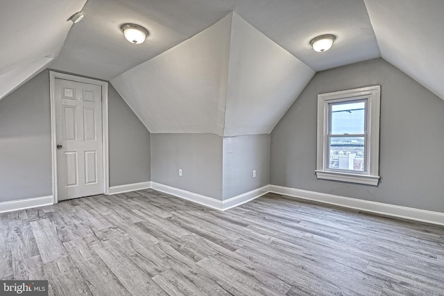 additional living space featuring light wood-type flooring and vaulted ceiling