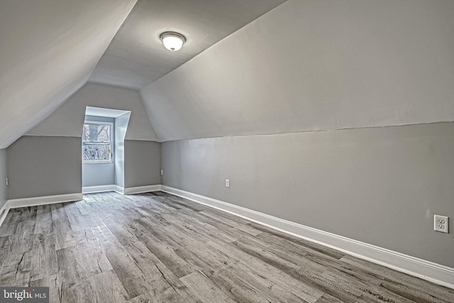 additional living space featuring vaulted ceiling and light wood-type flooring